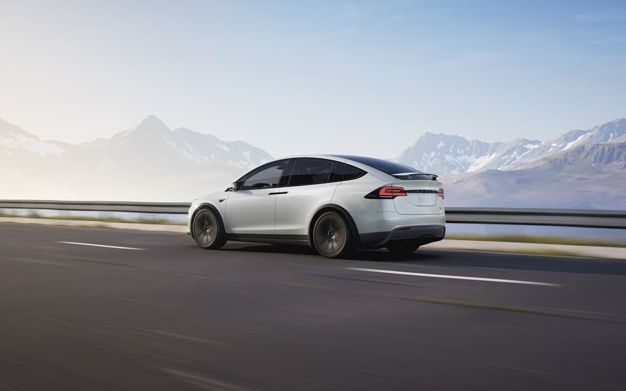 Tesla’s official photograph of a white Model X driving past mountains